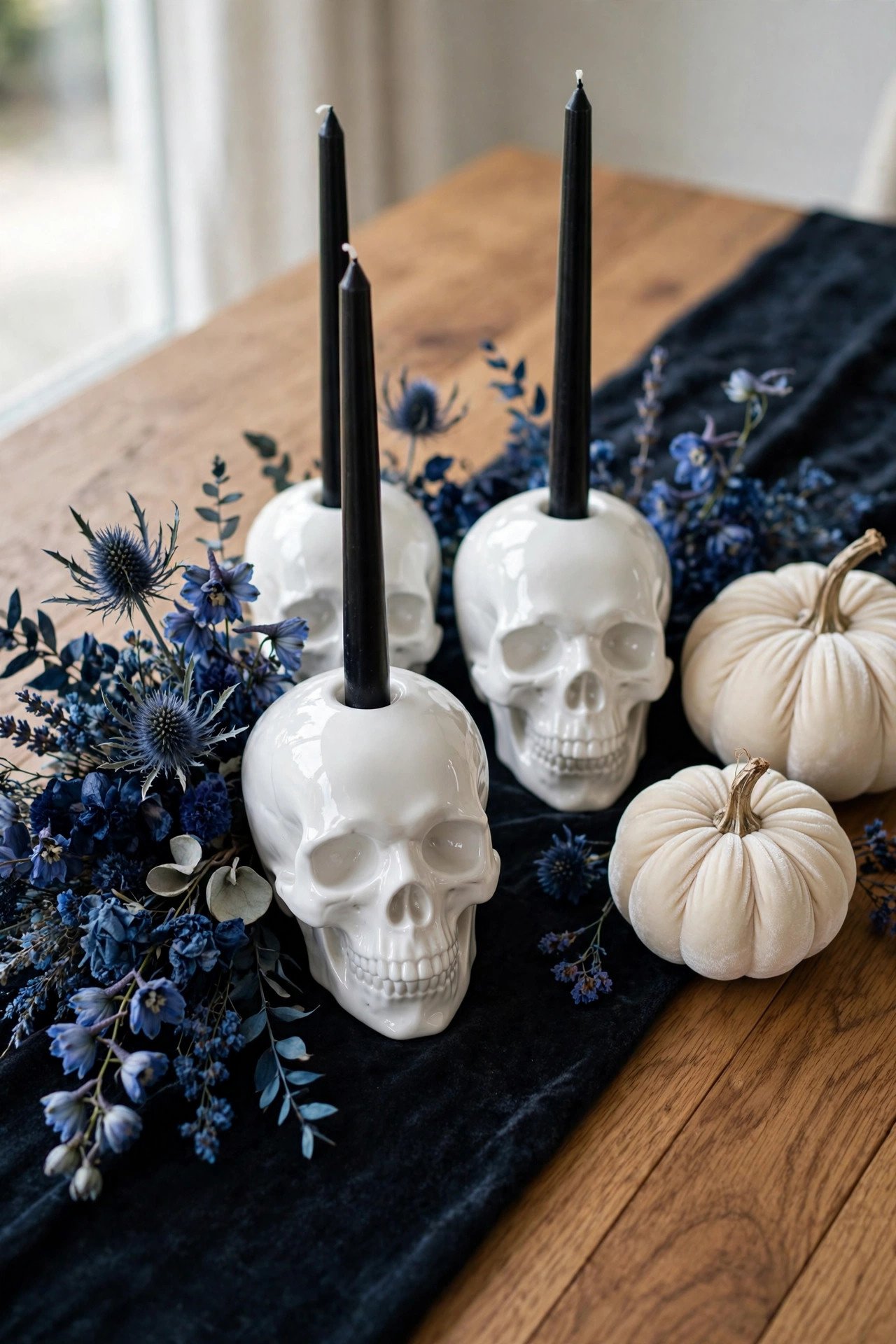 White skull candle holders with black candles on an elegant Halloween dinner table