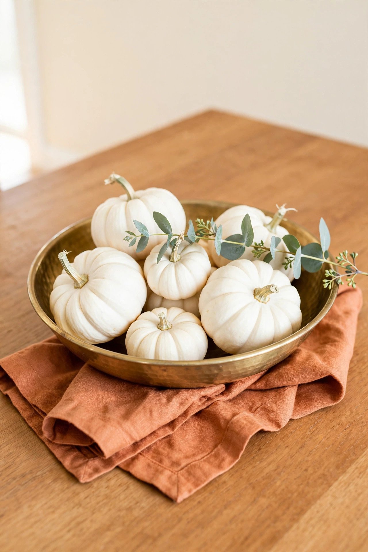 A brass bowl filled with white baby boo pumpkins