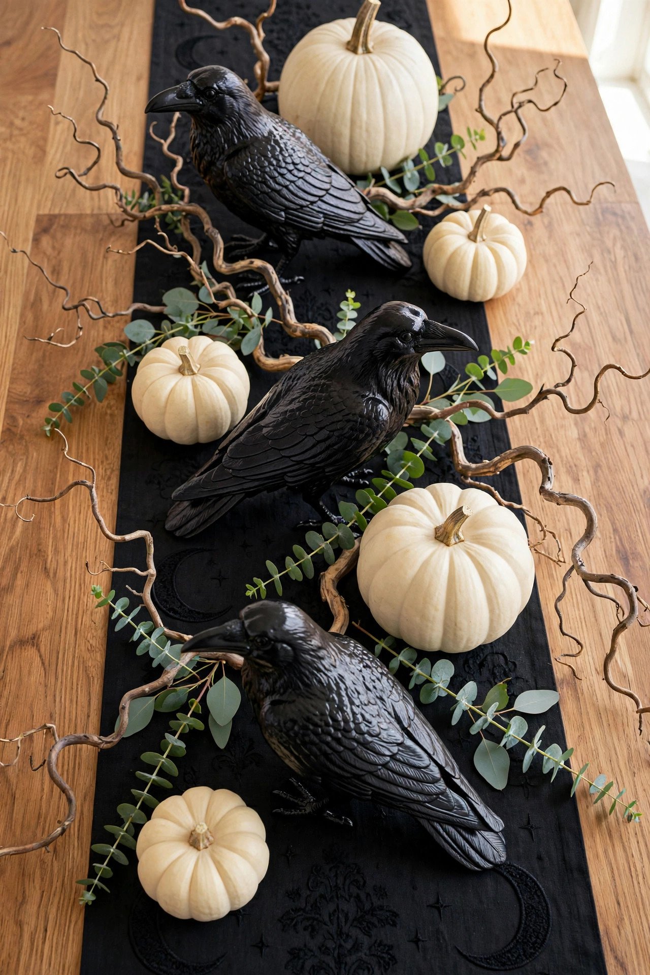 Black raven figurines perched among pumpkins and candles on a Halloween table runner